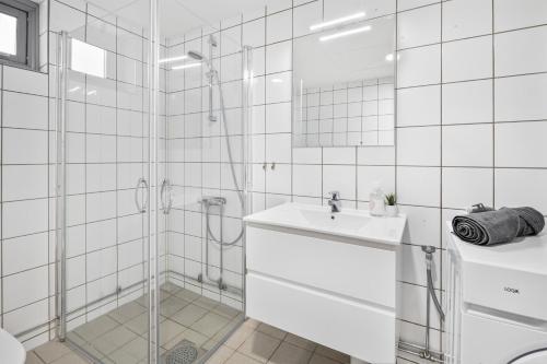 uma casa de banho branca com um chuveiro e um lavatório. em Forenom Serviced Apartments Oslo Munch em Oslo