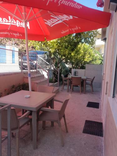 a table and chairs with a red umbrella on a patio at RIAN GUEST HOUSE in Sarandë