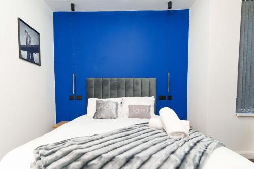 a bedroom with a blue accent wall and a bed at Spencer House in Leeds