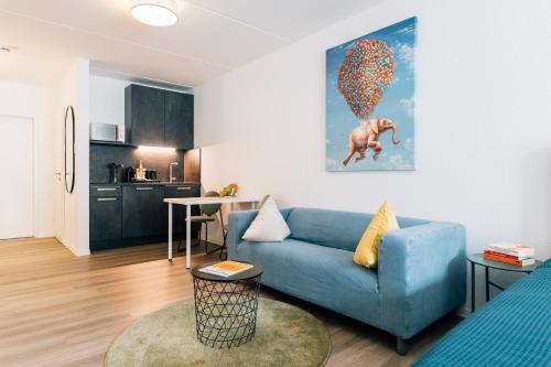 a living room with a blue couch and a kitchen at City - Travel & Living - Appartement in Bielefeld
