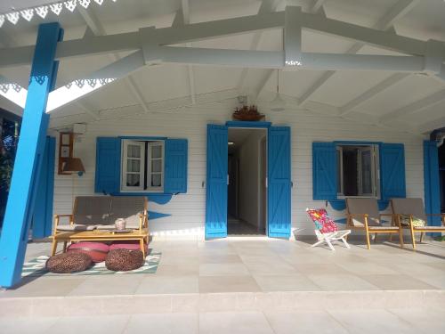 une terrasse couverte d'une maison avec des portes et des chaises bleues dans l'établissement La grenadine, à Sainte-Anne-les Hauts
