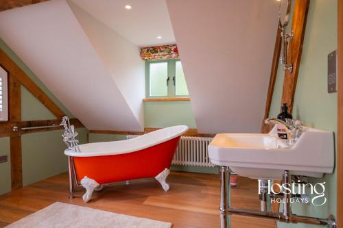 een badkamer met een rood bad en een wastafel bij Foxglove Barn - Rurally located 3 bed equestrian paradise in Aylesbury