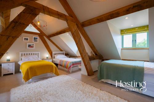 a attic bedroom with two beds and a window at Foxglove Barn - Rurally located 3 bed equestrian paradise in Aylesbury