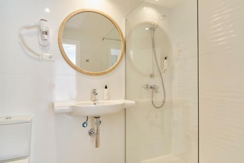 Baño blanco con lavabo y espejo en Excelsior Estudios & Apartamentos, en San Antonio