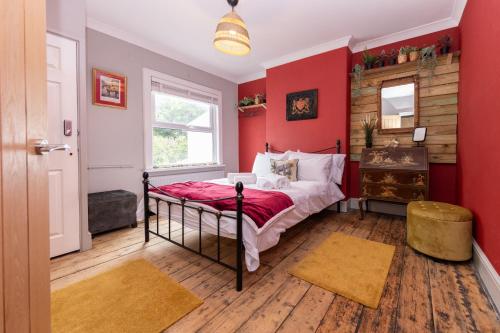 Schlafzimmer mit roten Wänden, einem Bett und einem Fenster in der Unterkunft James' Place at The Park in Merthyr Tydfil