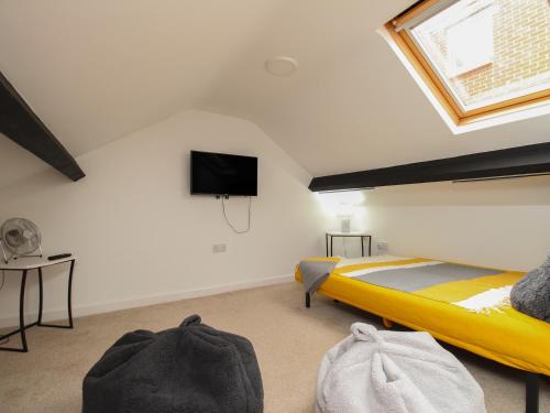 una camera con letto giallo e TV a schermo piatto di The Cottage a Weymouth