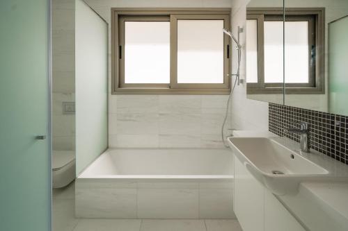 ein weißes Badezimmer mit einer Badewanne und einem Waschbecken in der Unterkunft Resitour - Karina Heights Villas in Tala