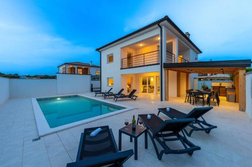 a patio with a pool and chairs and a house at Villa D&J in Vodnjan