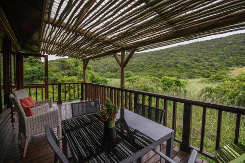 a balcony with a table and chairs and a view of the mountains at Thunzi Bush Lodge in Beachview