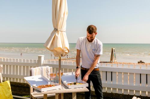a man standing next to a table with two boxes of food at The Beachcroft Hotel, BW Signature Collection in Bognor Regis