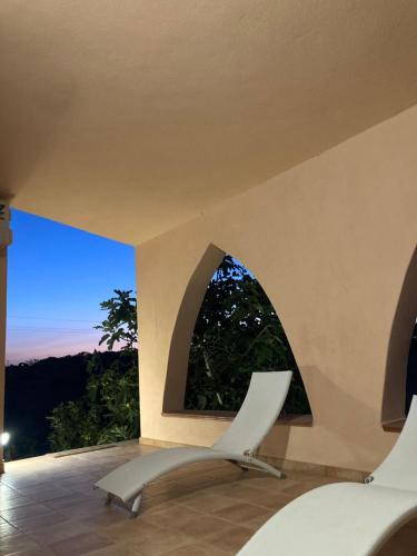 une chaise blanche dans une chambre avec fenêtre dans l'établissement Relax e tranquillità a Cala Pisana, à Lampedusa