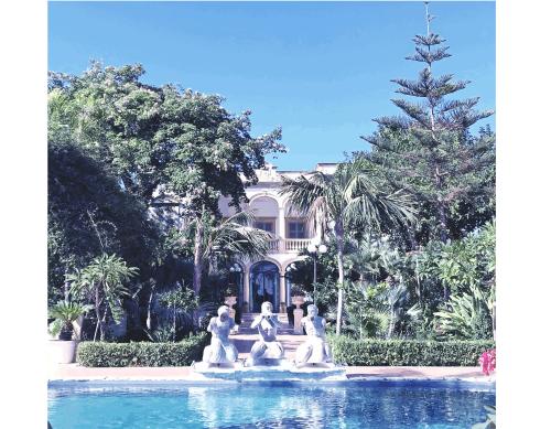 uma fonte com estátuas em frente a um edifício em VILLA MARRONE - Relais - em Marsala