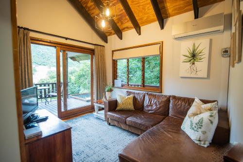 a living room with a brown couch and a tv at Thunzi Bush Lodge in Beachview