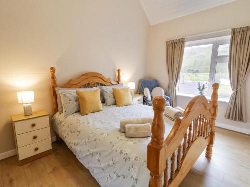 a bedroom with a wooden bed and a window at Maghera Caves Cottage in Ardara