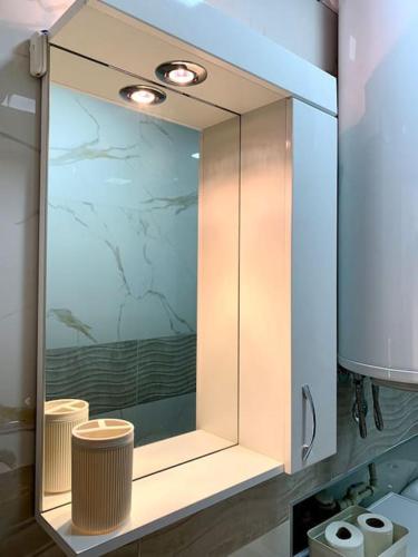 een witte kast met een spiegel in de badkamer bij Central City Apartment in Skopje