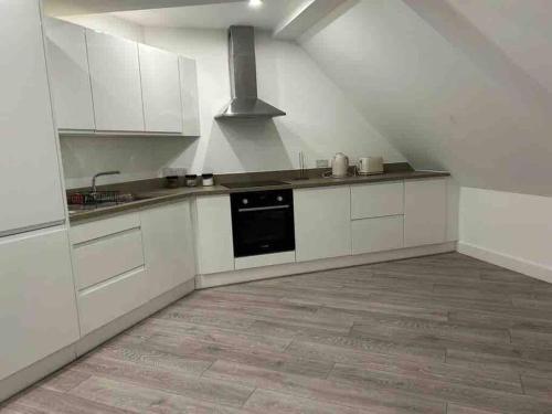 a large kitchen with white cabinets and a stove at stunning cinematic 2 bed in Hendon