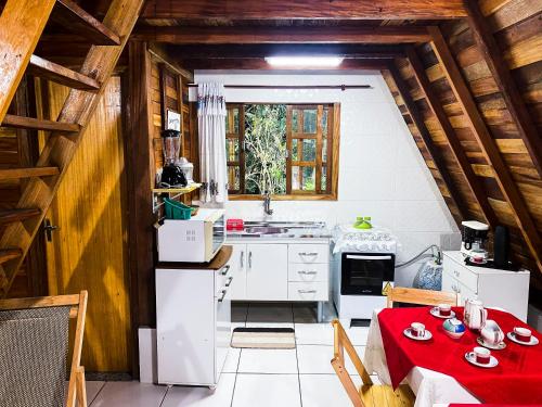 a kitchen with a table with a red table cloth at Chalé cercado de muito verde a 9km de Sto Antonio do Pinhal - Área rural in Santo Antônio do Pinhal