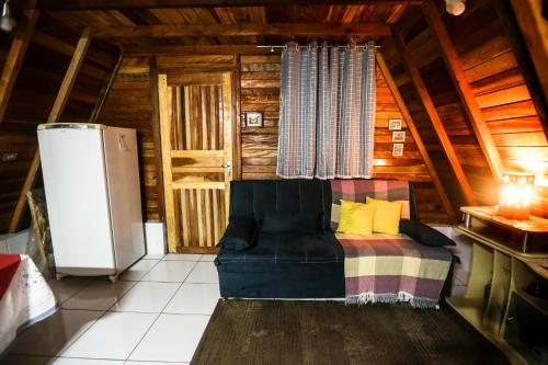 a living room with a couch and a refrigerator at Chalé cercado de muito verde a 9km de Sto Antonio do Pinhal - Área rural in Santo Antônio do Pinhal