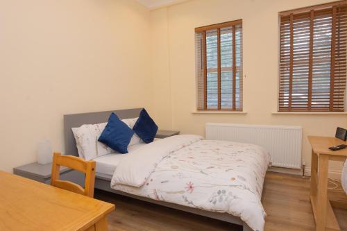 a bedroom with a bed with blue pillows on it at Evergreen Apartments- Flat 1, London in London