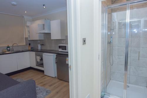 a kitchen with a walk in shower and a glass door at Evergreen Apartments- Flat 1, London in London