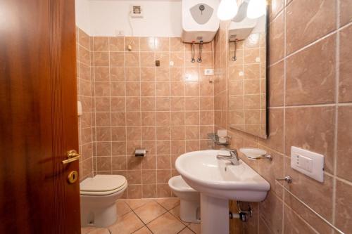 a bathroom with a sink and a toilet and a mirror at Kary Studio Apartment in Olbia