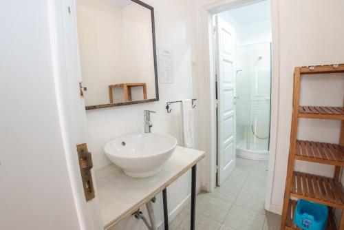 ein weißes Badezimmer mit einem Waschbecken und einem Spiegel in der Unterkunft Boho Guesthouse - Rooms & Apartments in Lissabon