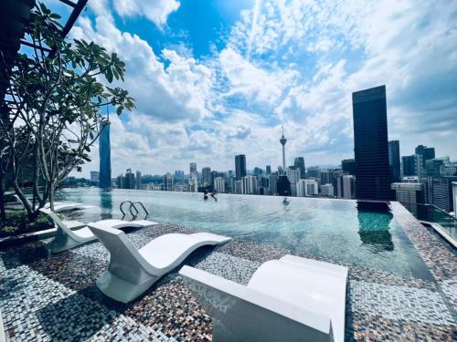 a swimming pool with chairs and a city skyline at Axon Serviced Suites Kuala Lumpur in Kuala Lumpur