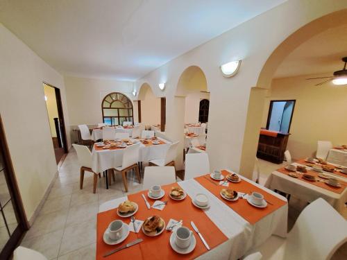 un comedor con mesas blancas y sillas blancas en Hotel Provincia en Trelew