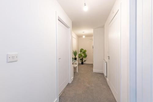 a hallway with white walls and a hallway with white doors at Gospel Heights by Guestz in Heswall