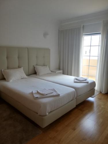 a bedroom with a large white bed with a window at Villa V2 V in Olhos de Água