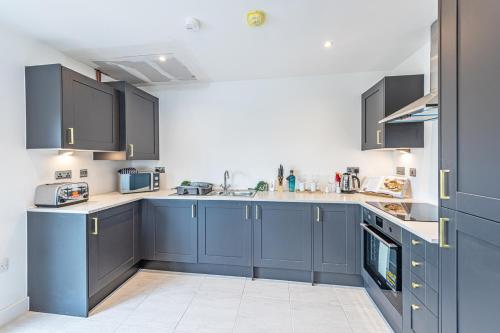 a large kitchen with blue cabinets and appliances at Gospel Heights by Guestz in Heswall