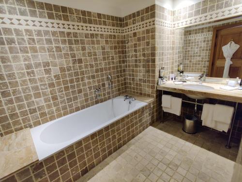 a bathroom with a bath tub and a sink at Hôtel de Bourgtheroulde, Autograph Collection in Rouen