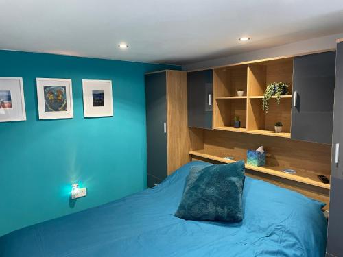 1 dormitorio azul con 1 cama con pared azul en Cosy cabin with private bathroom, 