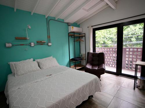 a bedroom with a white bed and a chair at CoLinkHouse Hotel in Medellín