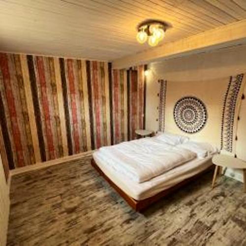 een slaapkamer met een bed in een kamer met gestreepte muren bij Maison de 3 chambres avec jardin clos et wifi a Morbier in Morbier
