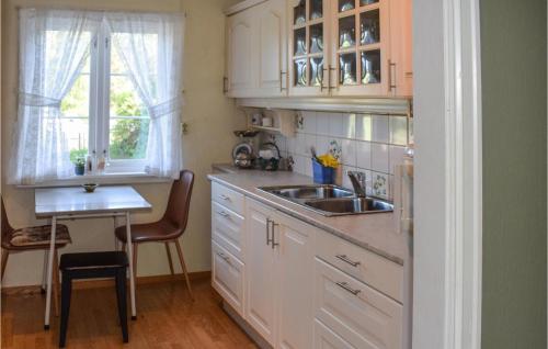 una cucina con armadi bianchi, lavandino e tavolo di Cozy Home In Stathelle With House A Panoramic View a Stathelle