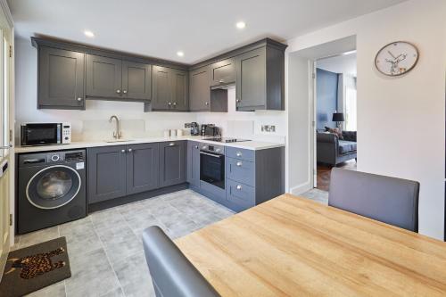 une cuisine avec des placards gris, une table et une salle à manger dans l'établissement Host & Stay - Castle View Cottage, à Barnard Castle