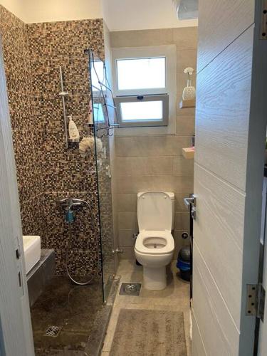 a small bathroom with a toilet and a shower at Gouna Pool view with rooftop living & BBQ grill in Hurghada
