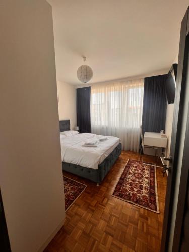 a bedroom with a bed and a table and a window at Apartament central Milea in Sibiu