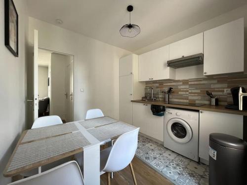 une cuisine avec une table et des chaises blanches ainsi qu'un lave-linge dans l'établissement Le Monterelais : Hypercentre, à Montereau-faut-Yonne