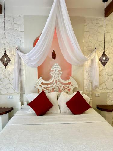 a bedroom with a white bed with red pillows at Pousada Lua de Charme in Canoa Quebrada