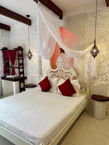 a bedroom with a large white bed with red pillows at Pousada Lua de Charme in Canoa Quebrada