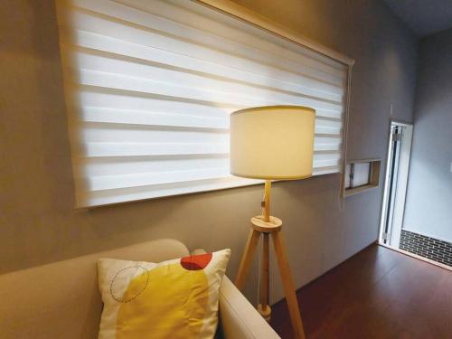 a lamp sitting next to a couch in a room at 日向サーフキャンプ101 in Hyuga