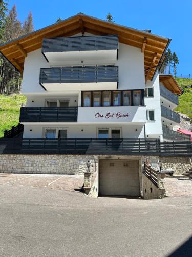 un edificio blanco con un garaje delante en Cèsa Sot Bosch, en Canazei