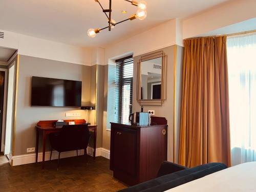 Habitación de hotel con cama, escritorio y TV. en Gatsby Hotel - Adults Only - Small Luxury Hotel - by F-Hotels en Blankenberge