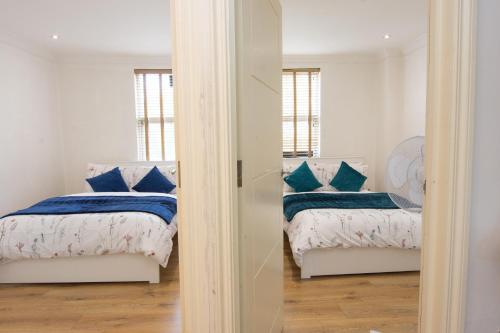 a bedroom with two beds with blue pillows at Evergreen Apartments-Flat 4, London in London