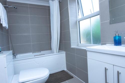 uma casa de banho com um WC, um lavatório e uma janela em Evergreen Apartments-Flat 4, London em Londres