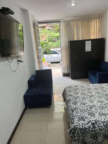 a bedroom with a bed and a chair and a tv at Apartaestudio cerca a Plaza Mayor in Medellín