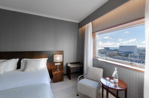 a bedroom with a bed and a window and a chair at Olissippo Oriente in Lisbon