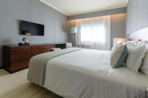 a bedroom with a large white bed and a television at Olissippo Oriente in Lisbon